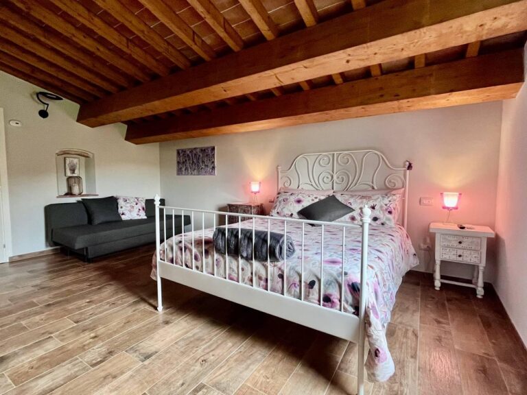 Camera quadrupla lilla con travi a vista e zona relax al Matana B&B